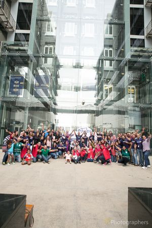 Energetic group photo with people cheering in modern glass building atrium.