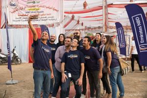 Group of people posing together at outdoor event with banners and flags.