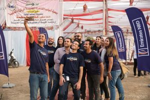 Team members celebrating at outdoor event with branded banners visible.