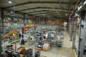 Large industrial manufacturing facility floor with automated equipment and machinery arranged in organized rows.