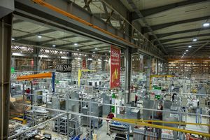 Expansive factory interior showing assembly lines and industrial equipment under overhead lighting.