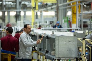 Manufacturing line workers assembling electronic equipment on a modern factory floor.