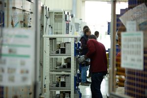 Workers inspecting electrical equipment in a manufacturing facility.