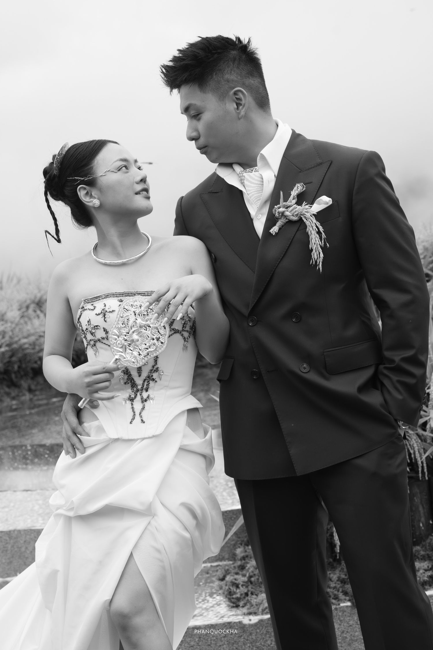Elegant black and white portrait of bride and groom sharing intimate moment in misty outdoor setting.