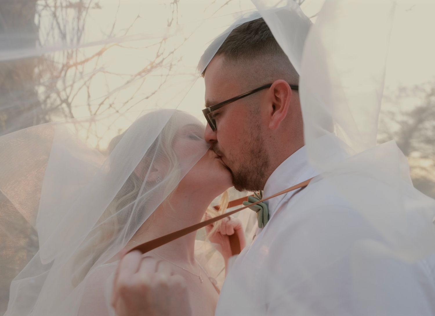 Newlywed couple shares intimate wedding moments in soft light with ethereal romantic style.