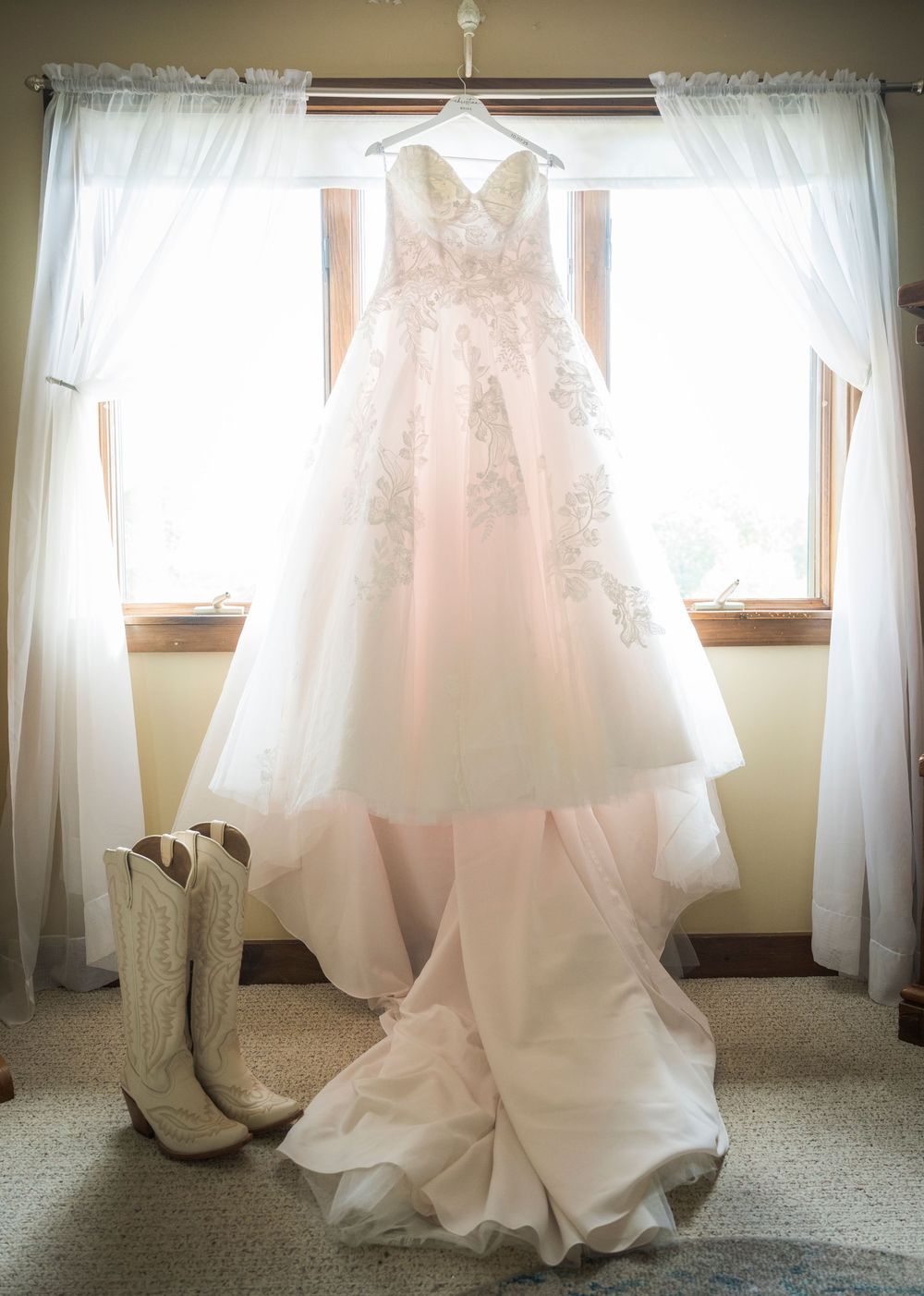 Wedding dresses displayed in sequence by a window, showing delicate white gowns with flowing fabric and intricate details.
