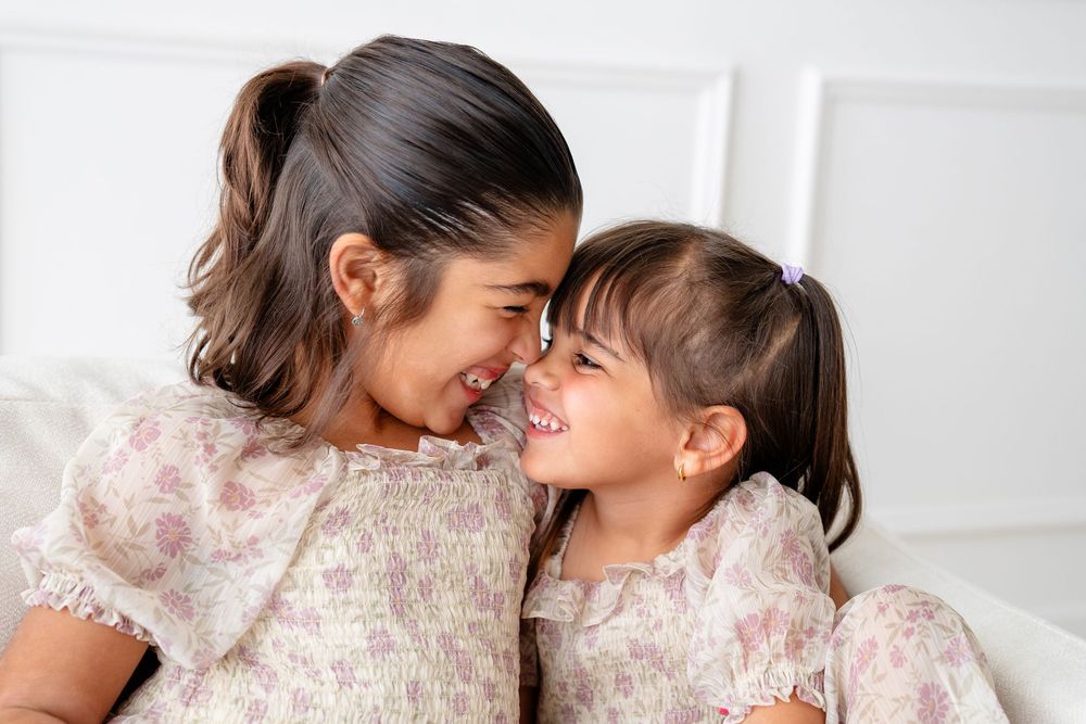 Side view of mother and daughter sharing a tender moment together with warm natural lighting and white wall background.