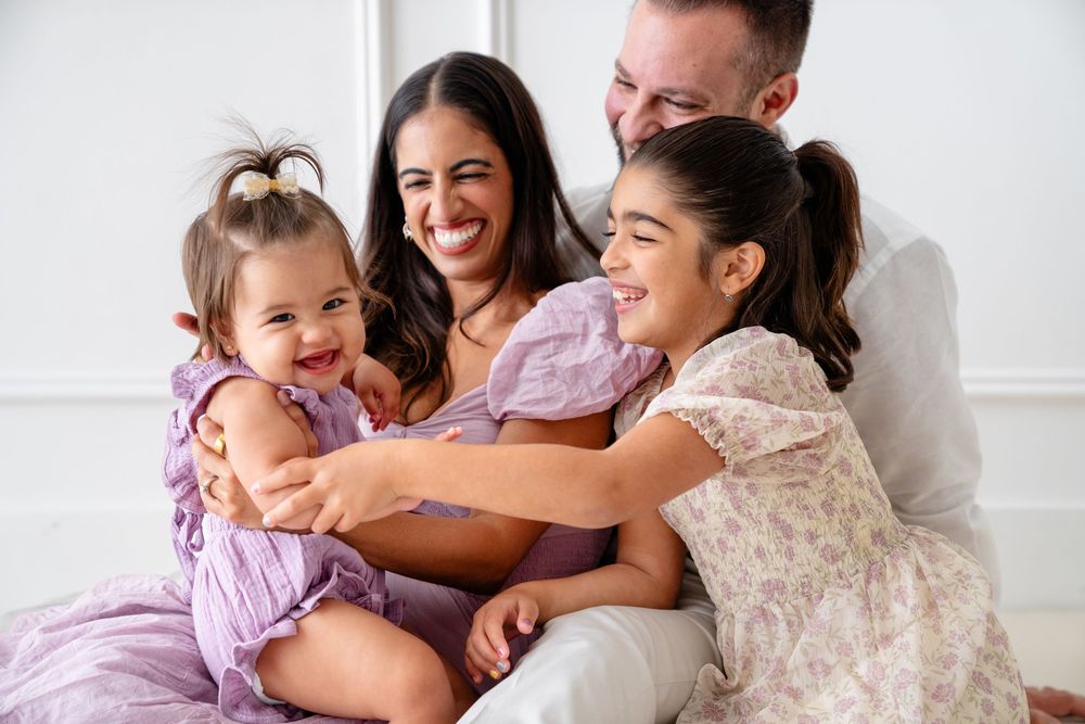 Family shares joyful moment together on floor during casual indoor photo shoot.