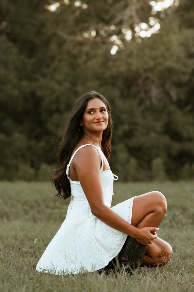 A white sundress creates an elegant silhouette against a natural grassy background in an outdoor portrait session.