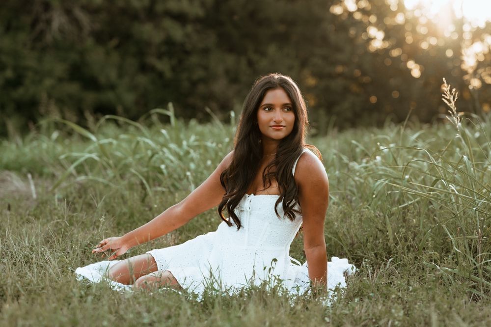 A serene outdoor photo session in white dress and boots amidst golden hour sunlight in a natural setting.