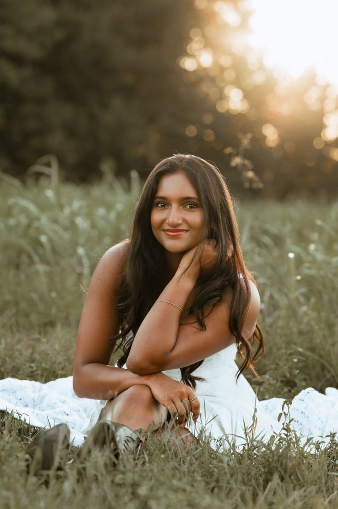 Sweet outdoor portrait session in a grassy meadow at golden hour with soft glowing bokeh background.
