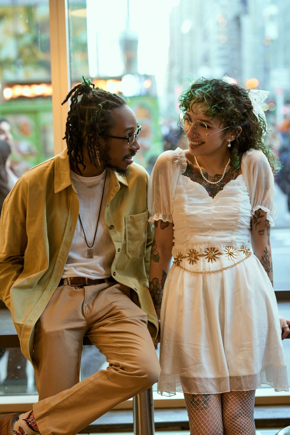 Two stylish people share a happy moment in casual vintage-inspired outfits with yellow jacket and white dress. Engagement shoot Manhattan