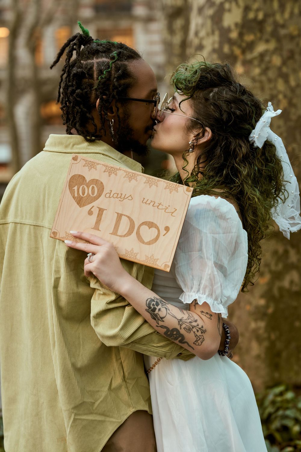 A series of romantic engagement photos showing a couple embracing and displaying a "we do" sign in an outdoor setting. Engagement shoot NYC