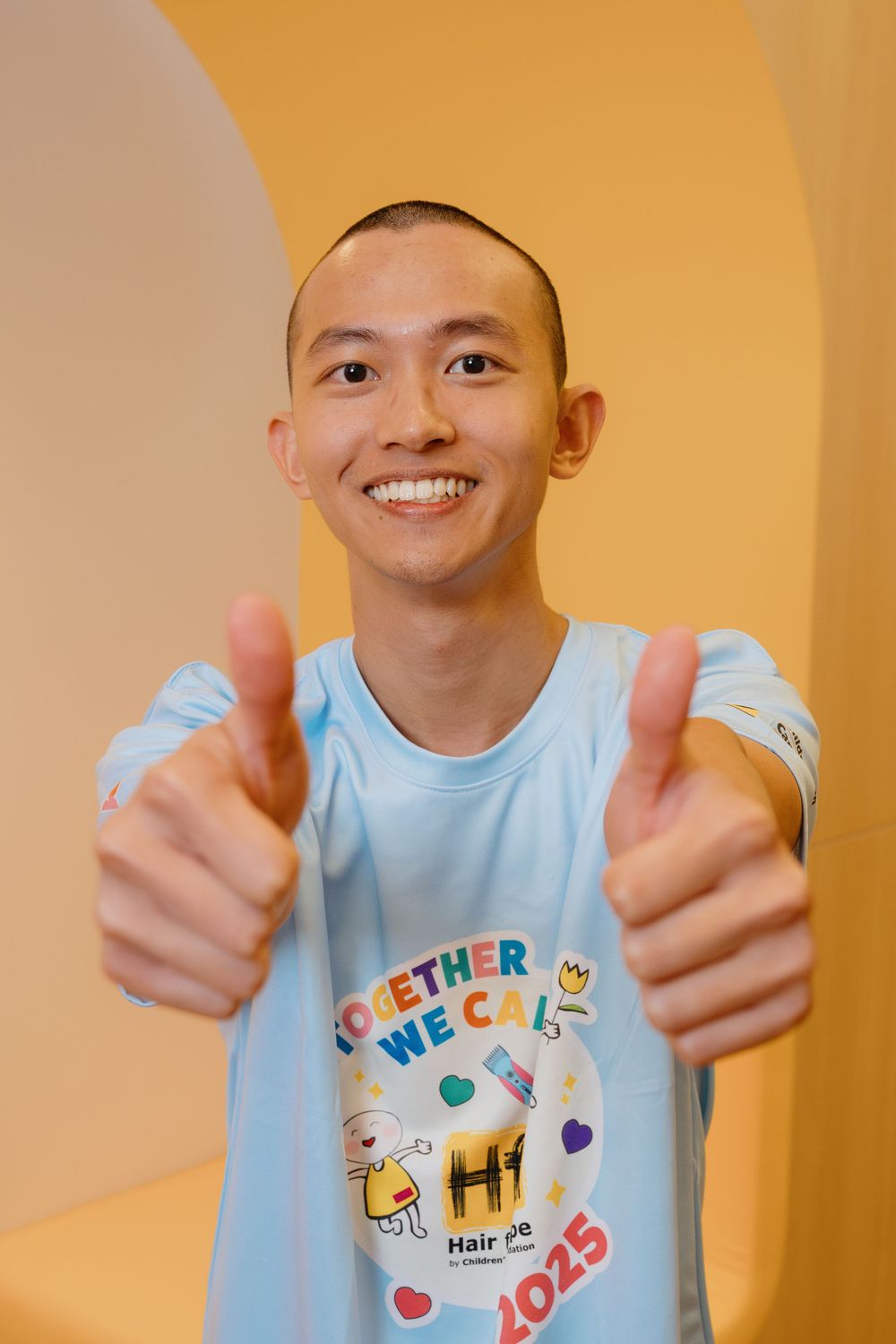Person wearing light blue t-shirt with "BETTER TOGETHER" text shows double thumbs up against orange background.