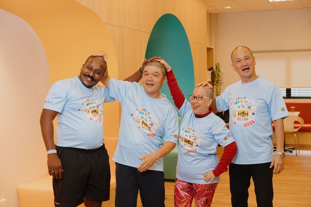 Group of people wearing light blue t-shirts engage in an animated conversation in a community room.