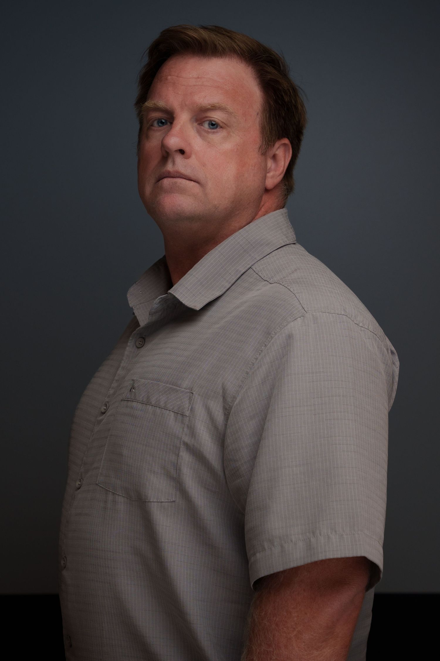 Dramatic low-key portrait series against dark background in business casual wear.