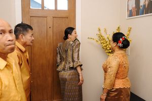 A yellow and gold traditional wedding or special event ceremony with guests in elegant attire and decorative elements.