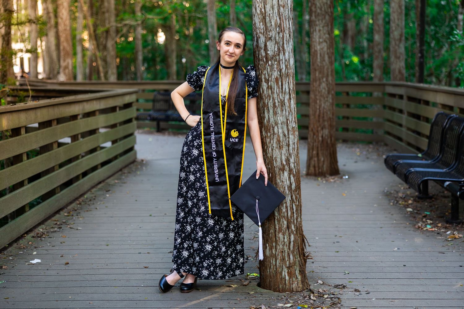 Young couple poses playfully near trees on a wooden boardwalk in a forest setting wearing casual attire.