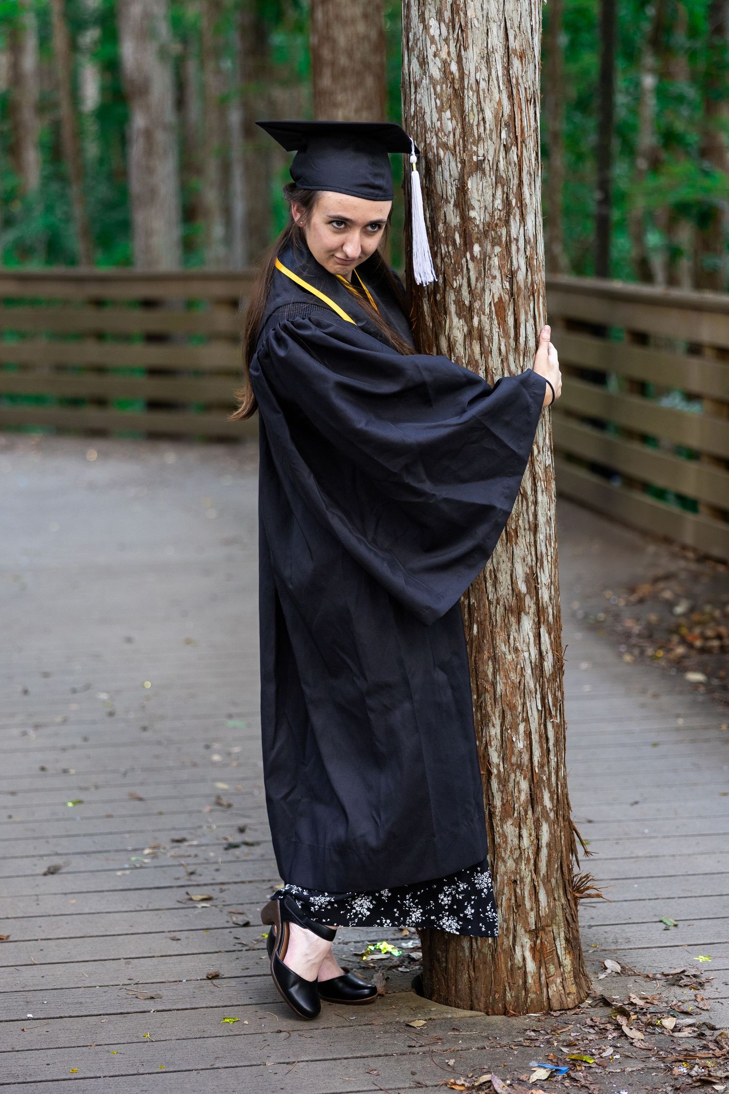 Creative graduation photo sequence showing poses against a wooden tree trunk walkway.