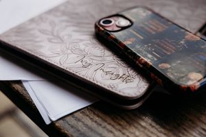 Several iPhone cases with a vintage floral design pattern arranged diagonally on a textured white surface.