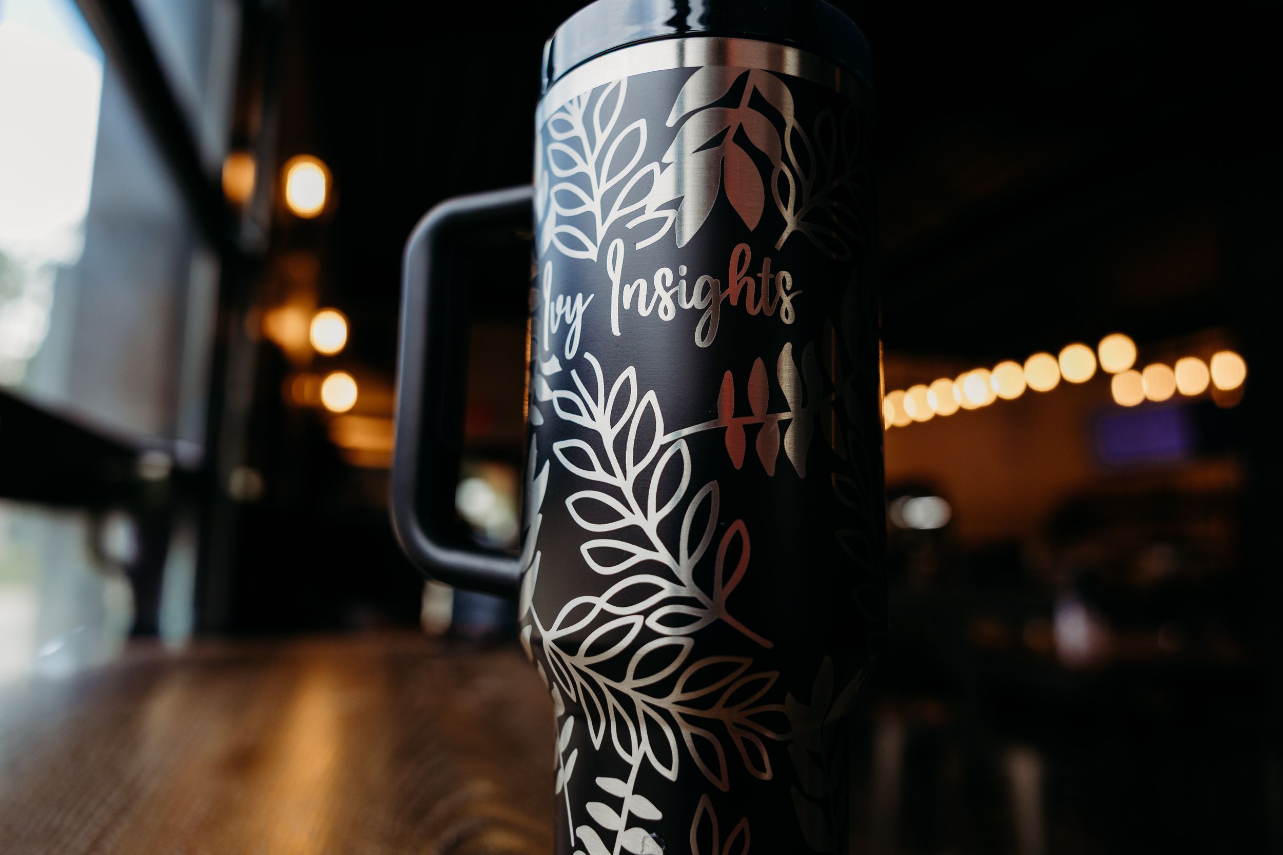 Close-up details of a beer glass with an etched floral pattern and white decorative designs against a dark background.