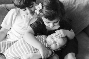 Vintage black and white photograph showing three children resting together on a couch.