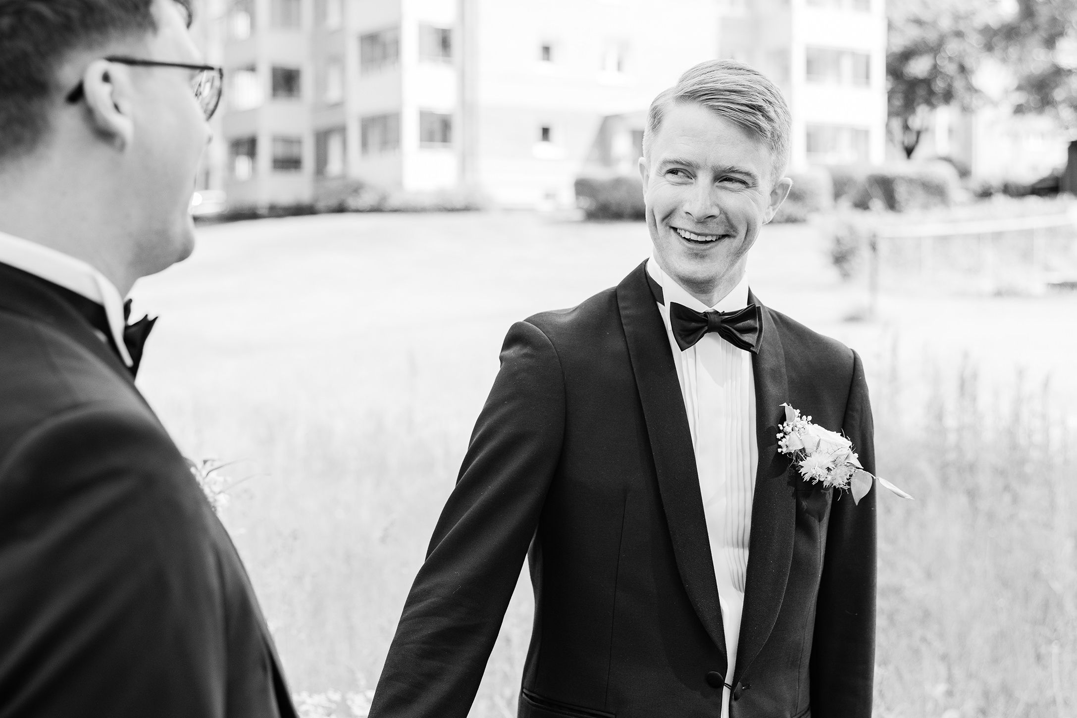 Nærbilde av brudgom som ser på mannen sin. I venstre kant ser vi bakhodet til mannen.