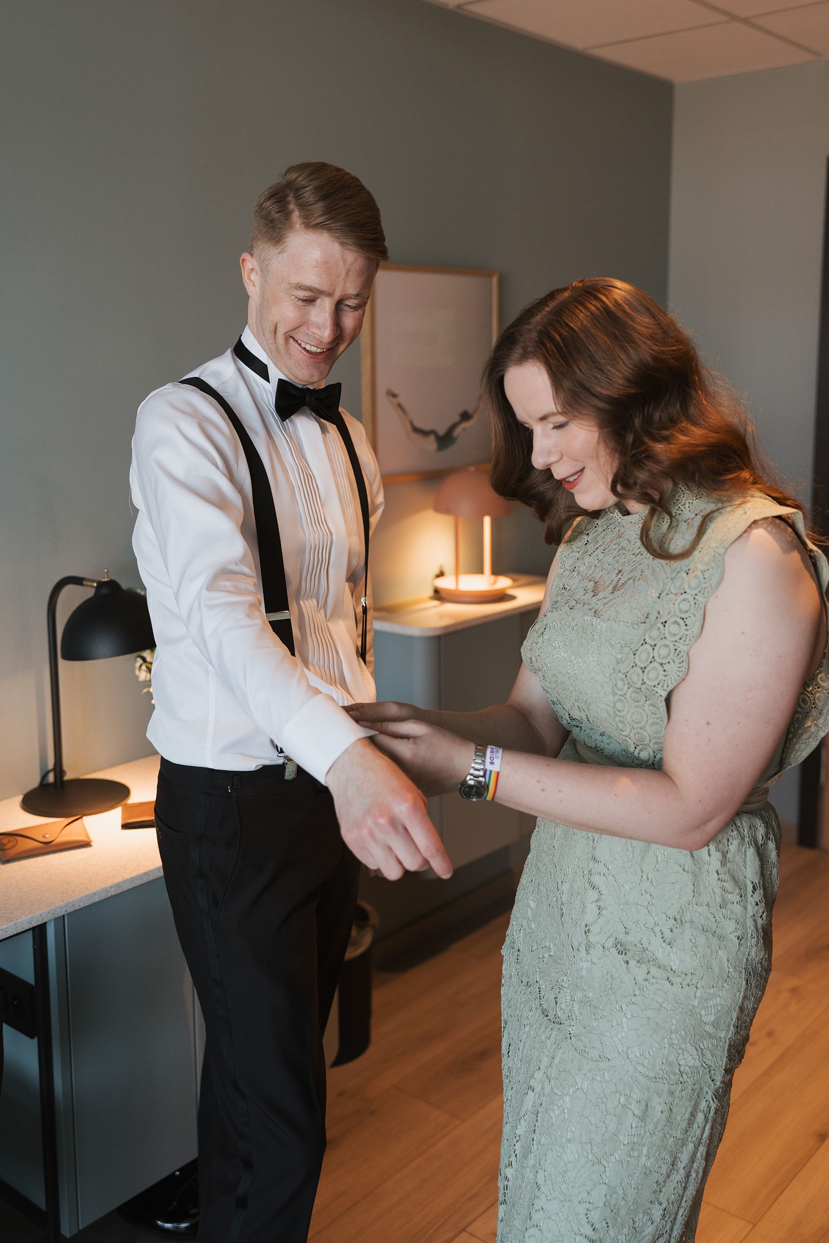 Forlover som hjelper brudgom med mansjettknappene. De står på hotellrommet for å gjøre seg klare.