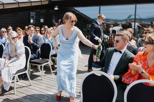Brudepike og brudesvenn som deler ut øl til gjestene rett før brudeparet kommer inn.