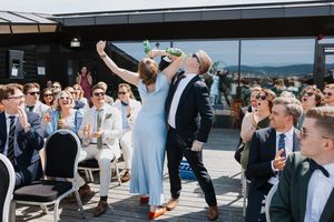Brudepike og brudesvenn som har arm i arm mens de drikker øl.