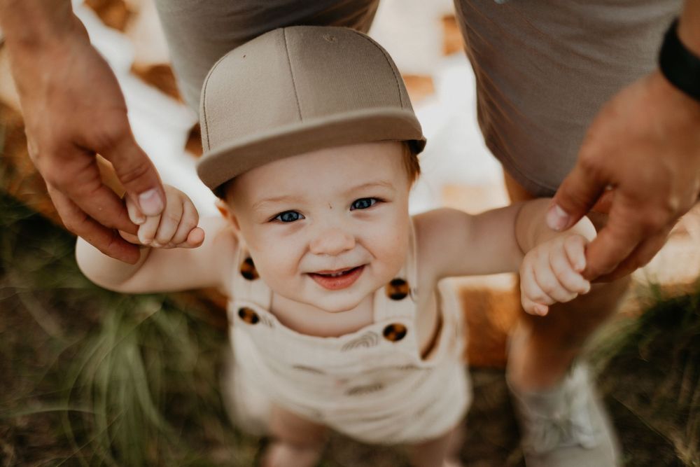 A collection of heartwarming family moments showing hands holding, hugging and playing with a small child outdoors.