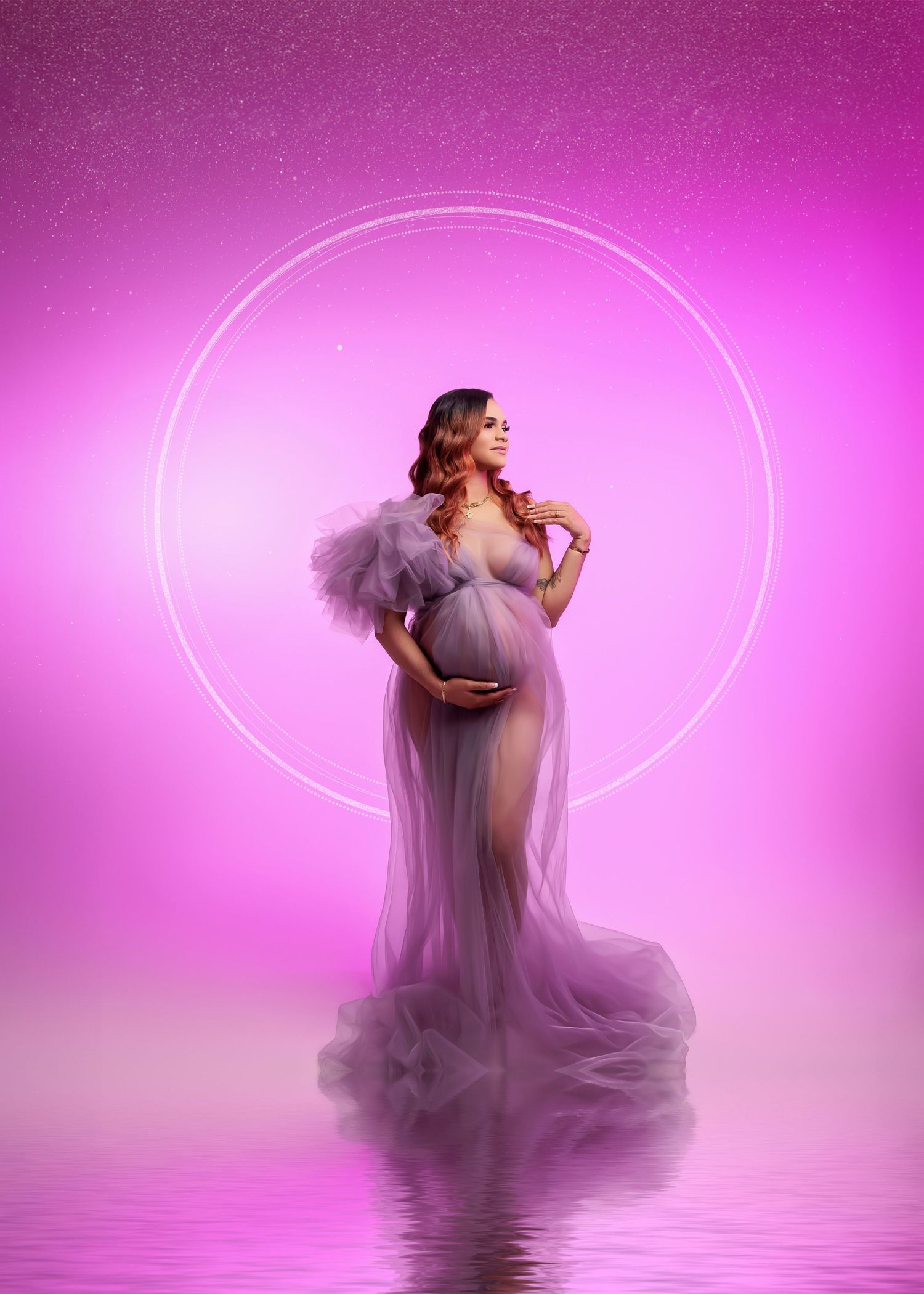 Pregnant woman in lavender tulle gown standing in glowing circle on pink background.