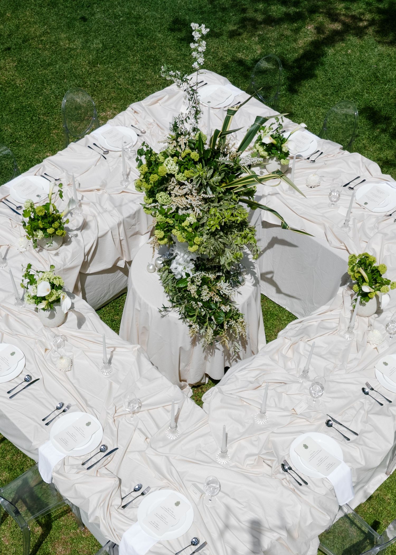 Elegant wedding place settings with white linens and fresh floral centerpieces arranged on grass outdoors at Al Ru Farm in Adelaide.