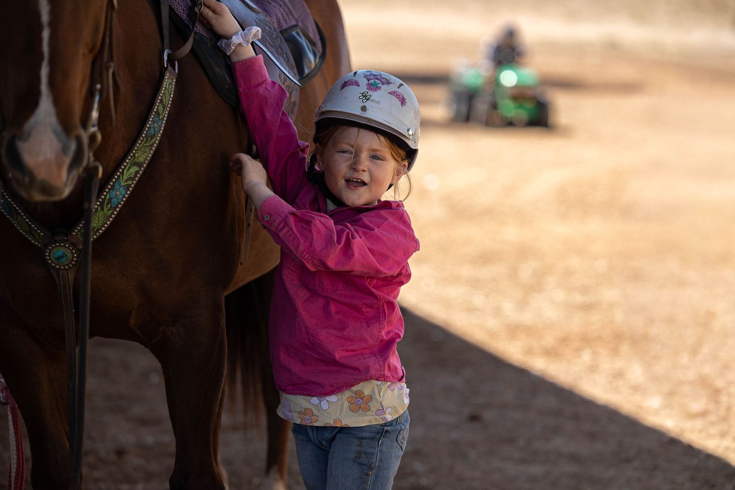 Little girl unsaddling her horse