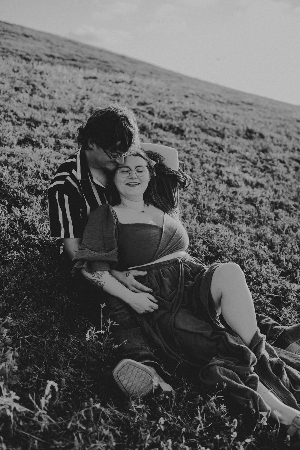 Black and white photos show a person relaxing in a grassy field on a sunny hillside.
