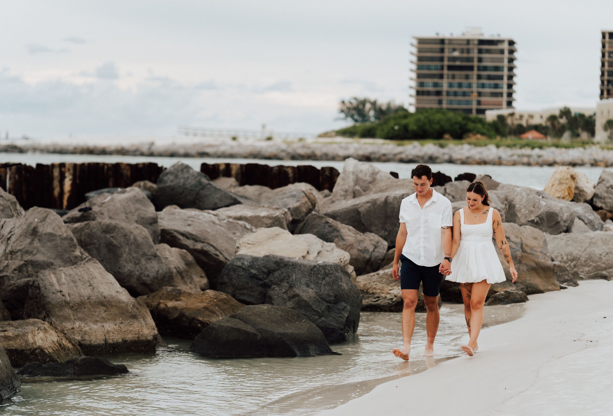 Coastal engagement photography in St. Pete Beach featuring a couple in white and blue outfits near tropical palms.