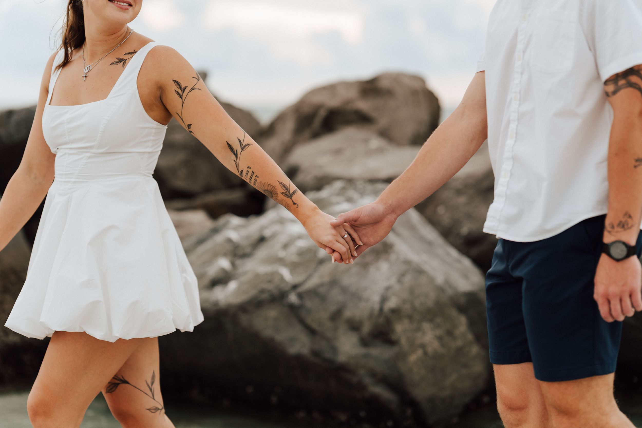 Coastal engagement photography in St. Pete Beach featuring a couple in white and blue outfits near tropical palms.