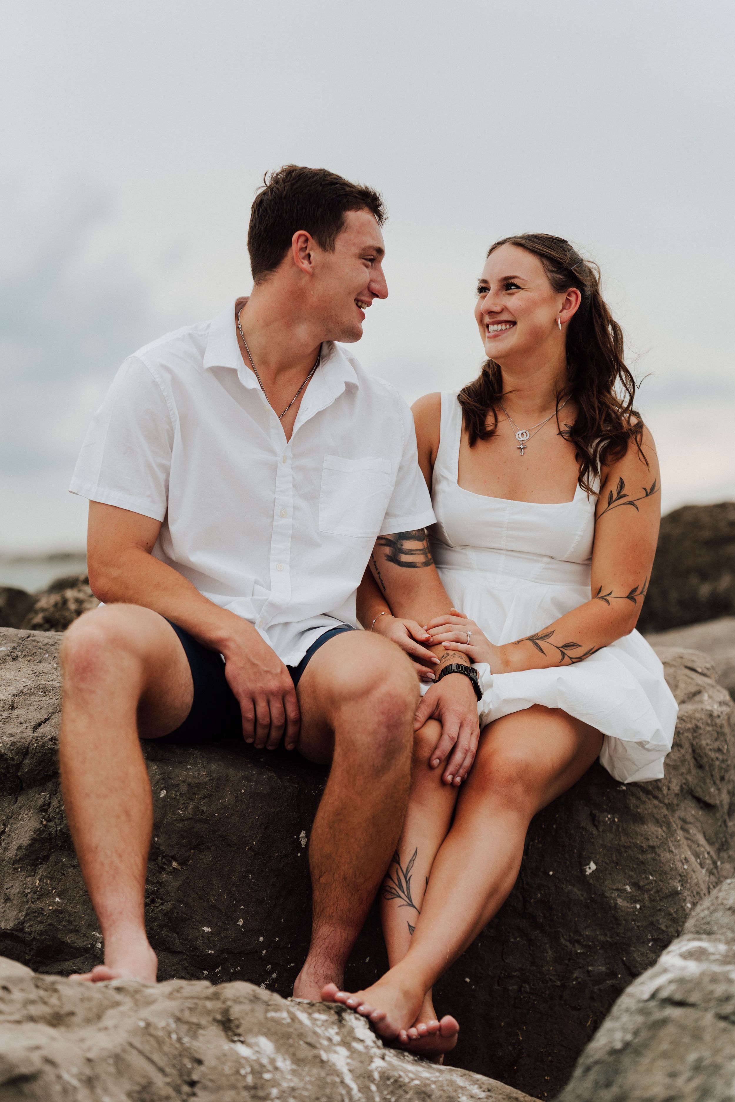 Coastal engagement photoshoot in St. Pete Beach featuring a couple in white and blue outfits near shore reef.
