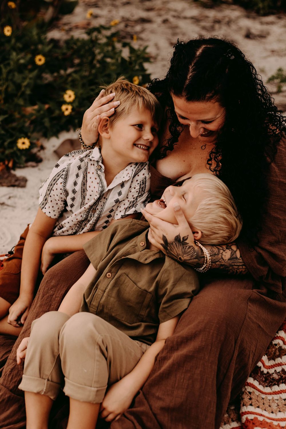 Candid sequence of tender moments between parent and child sitting on a blanket outdoors with sunflowers in background.