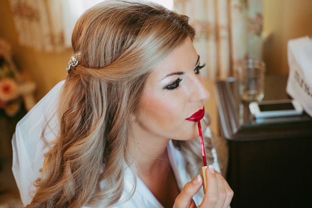 Professional makeup artist applying lipstick to model during beauty preparation session in studio.