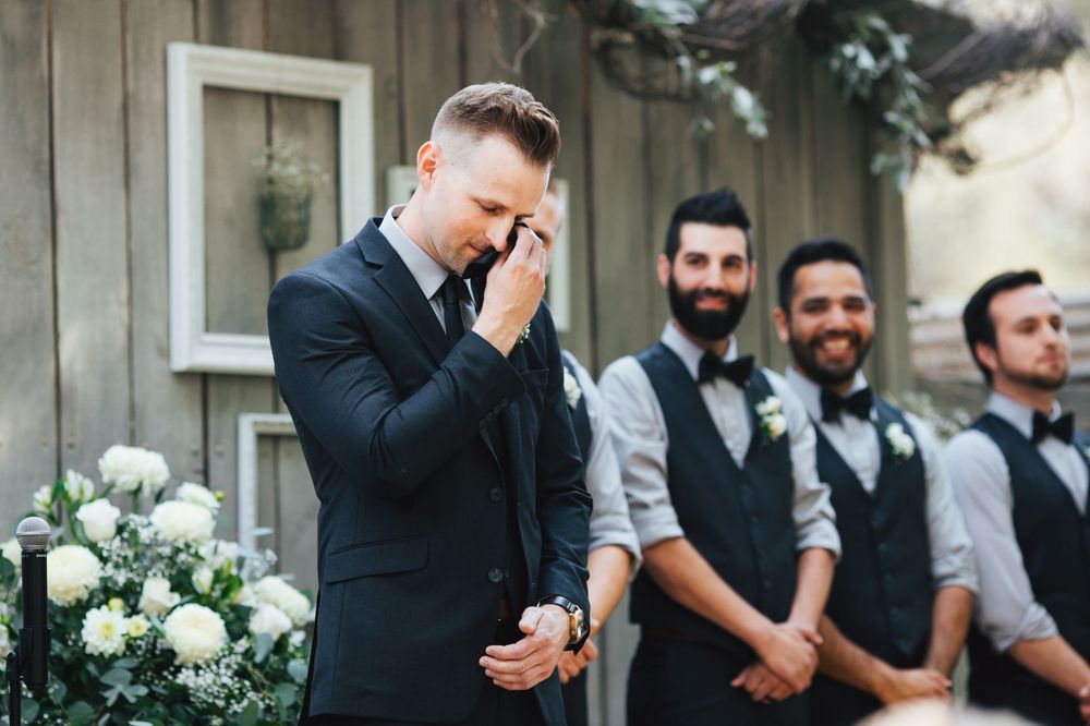 Wedding party in gray and black attire gathered outdoors for formal celebration photos.
