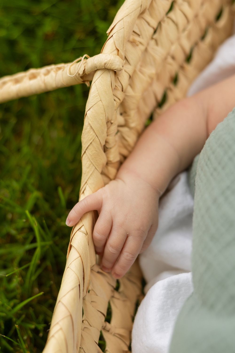 Close-up detail of woven basket edge with white fabric and green blanket.