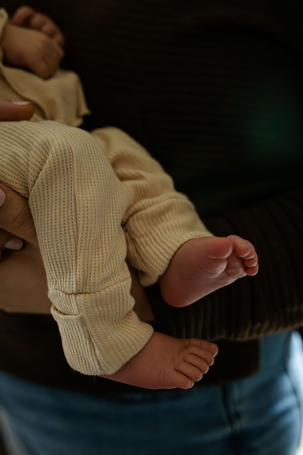 Close-up series of tiny baby feet in a white knit sweater against dark background.