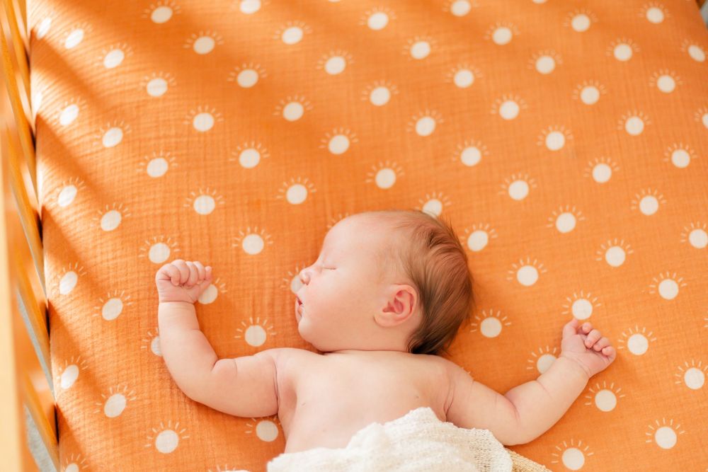Sleeping newborn baby on orange polka dot background in sequential photos.