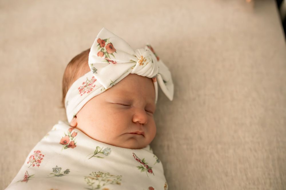 Newborn baby sleeping peacefully in floral print wrap.