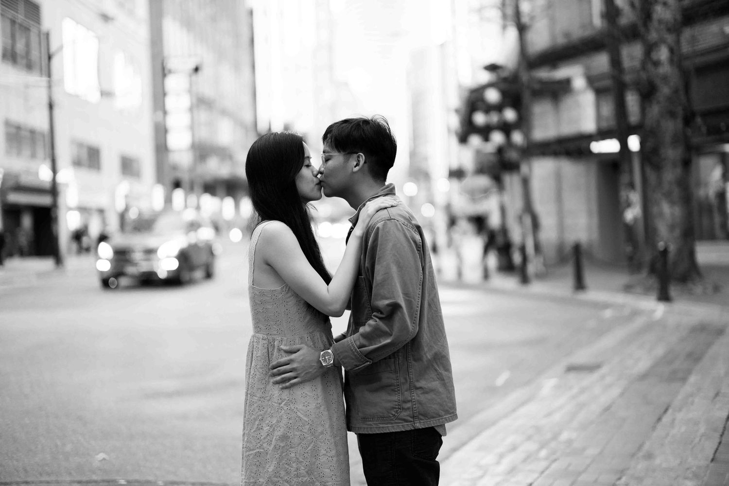 A romantic black and white photo of a couple sharing a tender moment on a city street.