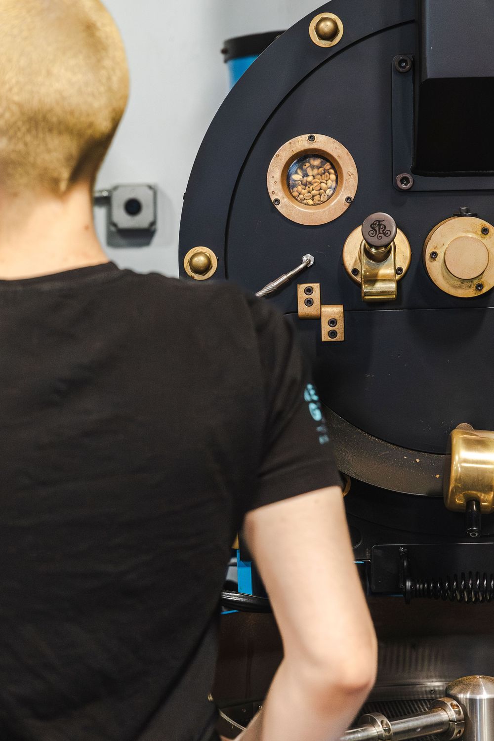 Close-up of a coffee roasting machine with brass and black metal components showing industrial details.