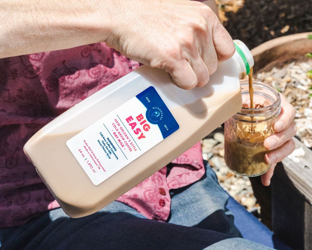 A hand pours a white liquid substance from a plastic bottle onto a surface.