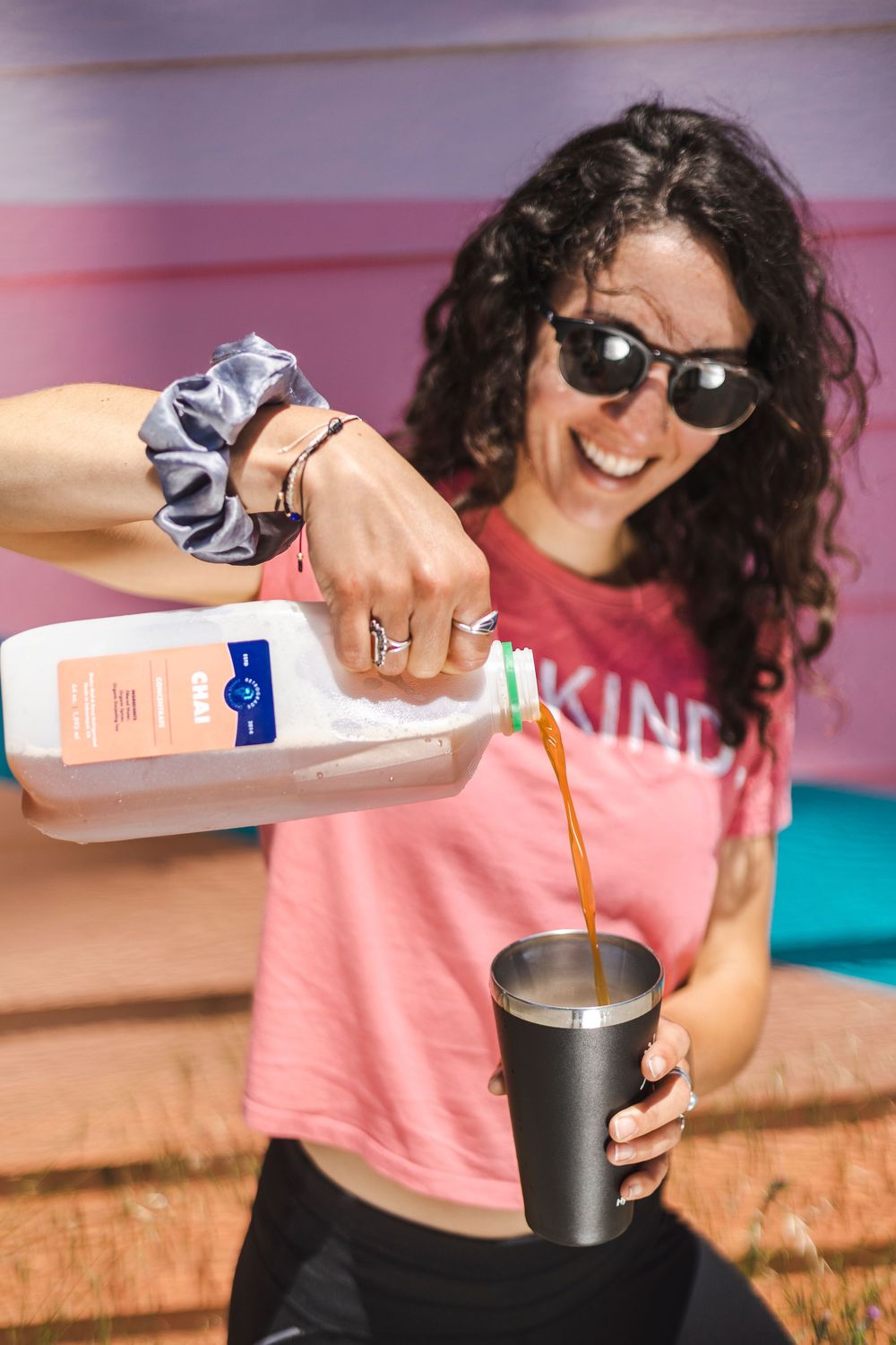 Person in pink shirt and sunglasses pours milk into a dark cup in a sequence of connected photos.
