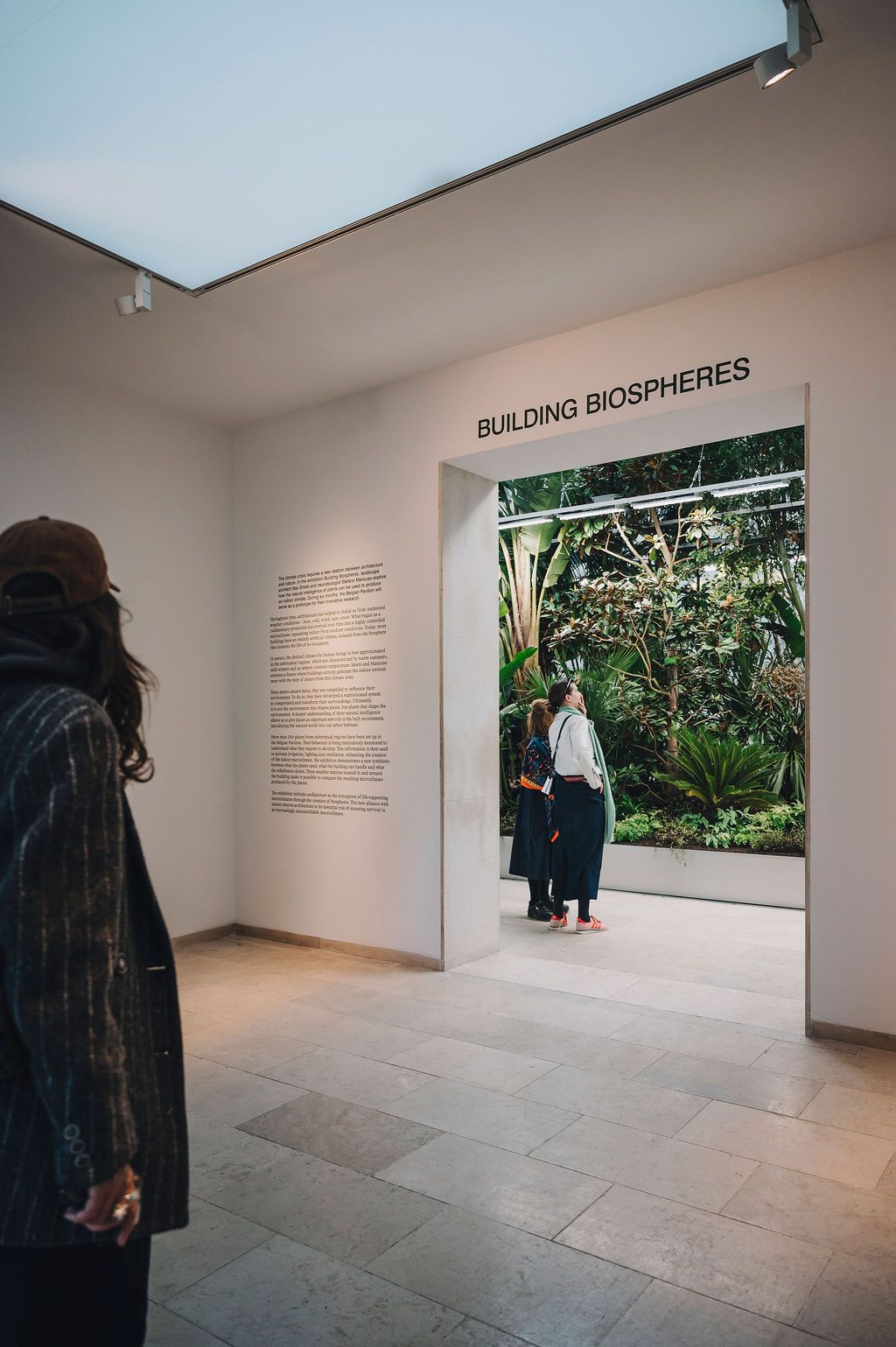 Visitatori del Padiglione Belgio che osservano l'allestimento sulle biosfere alla Biennale di Venezia